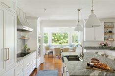 a kitchen filled with lots of white cabinets and counter top next to a dining room table