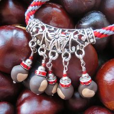 the beads are hanging from the necklace on the beaded bracelet with red and white cords