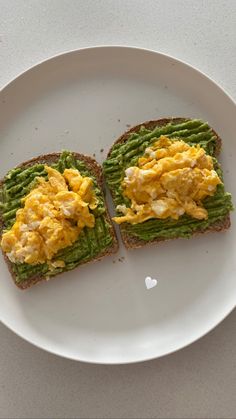 two pieces of toast with eggs and green beans on it sitting on a white plate