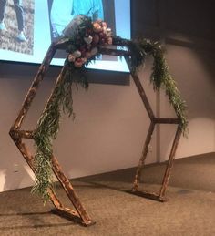 a wooden structure with branches and flowers in front of a projector screen