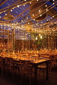 an outdoor dining area with string lights strung across the ceiling and tables set for dinner