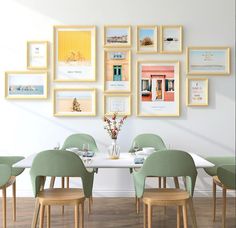 a dining room table surrounded by green chairs and pictures on the wall above it that have been framed with yellow frames