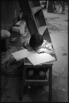 a young boy sitting at a desk writing on paper