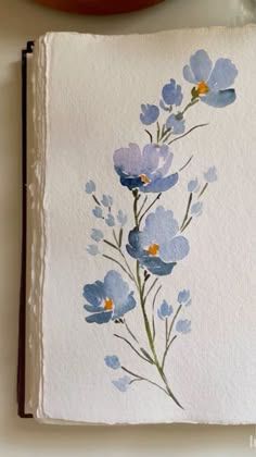 an open book with blue flowers painted on it