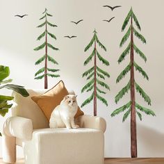 a white cat sitting on top of a chair in front of a wall with trees