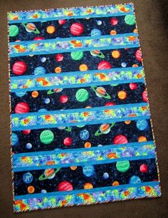 a piece of fabric with planets and stars in the sky on top of black ground