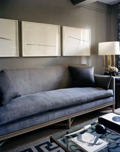 a living room filled with furniture and two paintings on the wall above it's coffee table