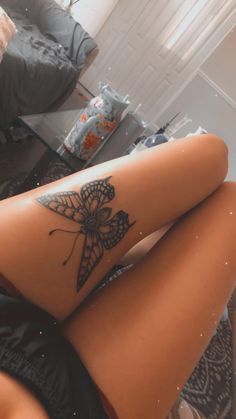 a woman's leg with a butterfly tattoo on it sitting in front of a mirror