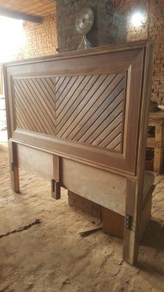 a large wooden bed frame sitting in the middle of a room with brick walls and flooring