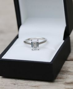 an engagement ring in a black box on a wooden table