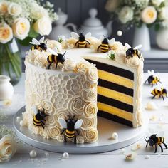 a white cake with yellow and black frosting has bees on it next to flowers