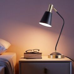 a bedside table with a lamp on it next to a bed