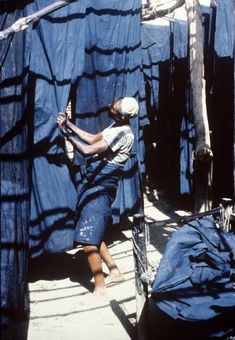 a woman standing in front of some blue tarp covered walls and holding a stick