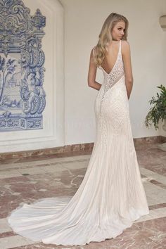 a woman in a wedding dress standing on a tile floor with her back to the camera