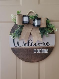 a welcome to our home sign hanging on a door with burlocks and greenery