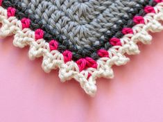 a crocheted doily on a pink surface with white and black trims