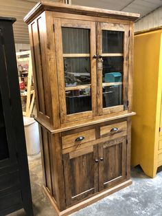 a large wooden cabinet with glass doors and drawers in a room filled with other furniture