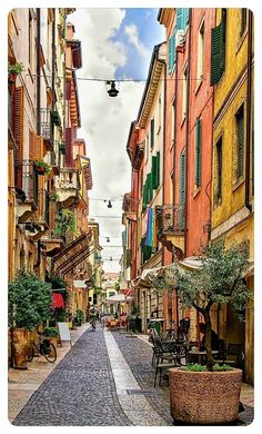 a cobblestone street with tables and chairs on both sides in an old european city