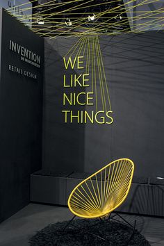 a yellow chair sitting on top of a black floor next to a sign that says we like nice things