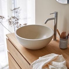 a white bowl sink sitting on top of a wooden counter next to a toilet paper roll