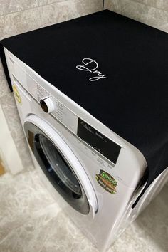 a white washer sitting next to a dryer on top of a tiled floor