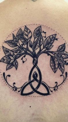 the back of a woman's shoulder with a tree and two leaves on it