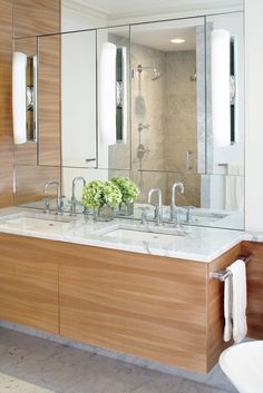 a bathroom with two sinks, mirrors and a large mirror above it's sink