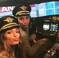 a man and woman sitting in the cockpit of an airplane with pilot's hats on