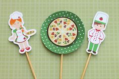 three little stickers with pizza on them are sitting on a green plate and one is holding a fork