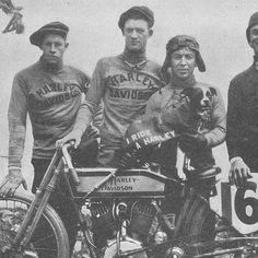 three men standing next to each other with a dog on a motorcycle in front of them