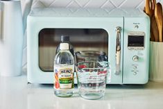 a microwave oven sitting on top of a counter next to a measuring cup and utensils