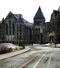 an empty street in front of some very old buildings with snow on the ground and trees