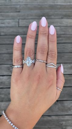 a woman's hand with three different rings on her fingers and two diamond bracelets