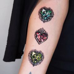 three heart shaped tattoos on the left arm and right arm, all in different colors