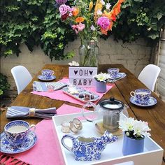 a table set with blue and white dishes, flowers in a vase and baby's breath tea cups