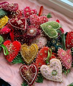 a pile of heart shaped ornaments on a pink cloth next to a window sill