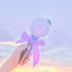 a hand holding a magnifying glass with a pink bow