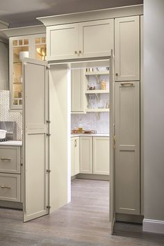 an open door leading to a kitchen with beige cabinets and white counter tops on the walls