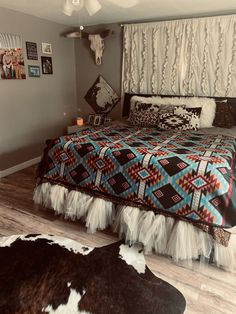 a bedroom with a bed, rugs and pictures on the wall above it is decorated in native american style