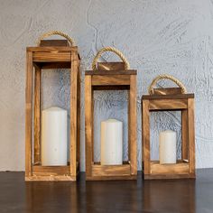 two wooden lanterns sitting on top of a table next to each other with white candles in them