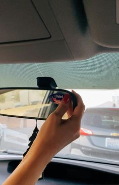 a person is holding their cell phone while driving in a car with other cars behind them