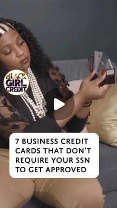 a woman sitting on top of a couch holding a cell phone and looking at her credit card