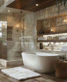 a bathroom with stone walls and flooring is shown in this image, there are towels on the shelf next to the bathtub