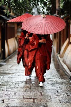 two people walking down the street with umbrellas over their heads