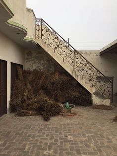 a fire hydrant sitting next to a pile of hay on the side of a building