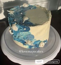 a blue and white cake with seashells on the top is sitting on a plate