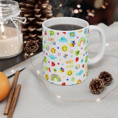 a cup of coffee sitting on top of a table next to pine cones and candles