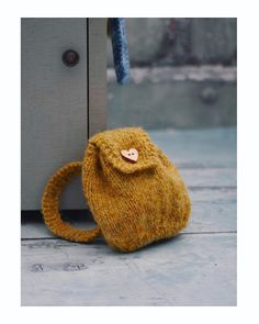 a small yellow bag sitting on top of a wooden floor next to a door handle