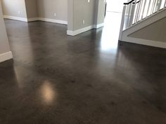 an empty living room with gray floors and white railings