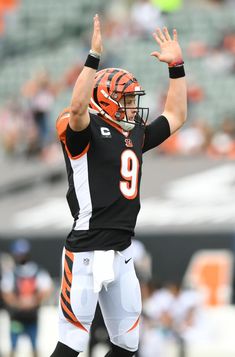 a football player throwing a ball in the air with his hand up to catch it